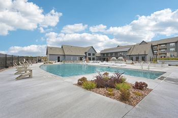 A large outdoor swimming pool surrounded by a concrete patio and a small garden.at The Garrison Luxury Apartment Homes, Colorado